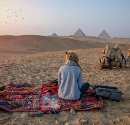 Woman watches sunset at the Giza Pyramids, she looks across